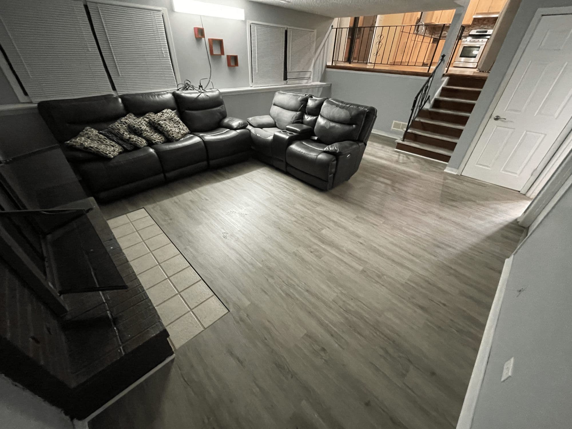 Gray plank flooring, white trim and a fireplace in a refreshed lower-level family room